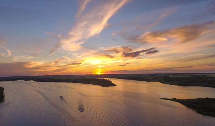 Stunning areial view of a sunset over a lake with two boats cruising on the lake